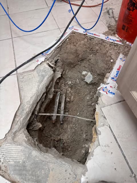 Concrete slab cut open to expose and repair underground plumbing pipes