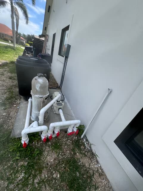 Water softener and filtration system with white PVC piping mounted on an exterior wall