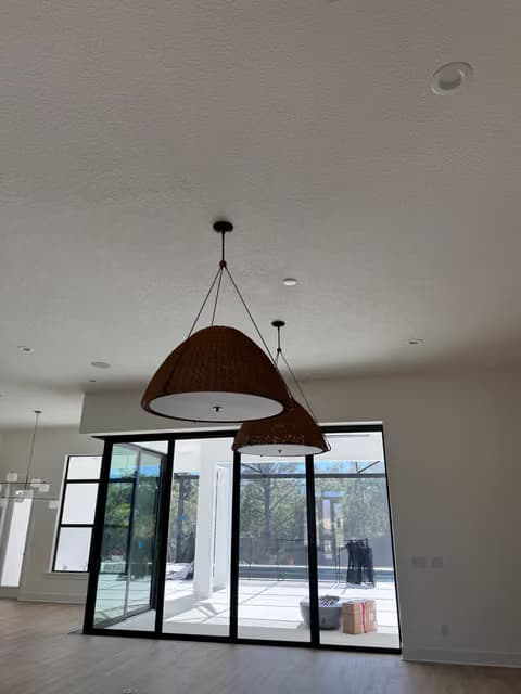 Wood pendant light fixture installed in a bright room with black-framed windows