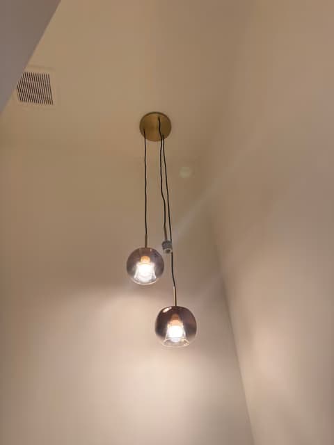 Two glass globe pendant lights hanging in a stairwell