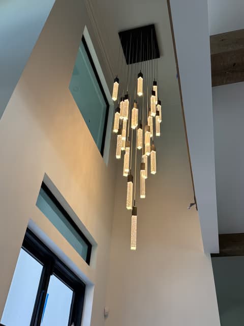 Modern linear chandelier with glass rod pendants installed near a window