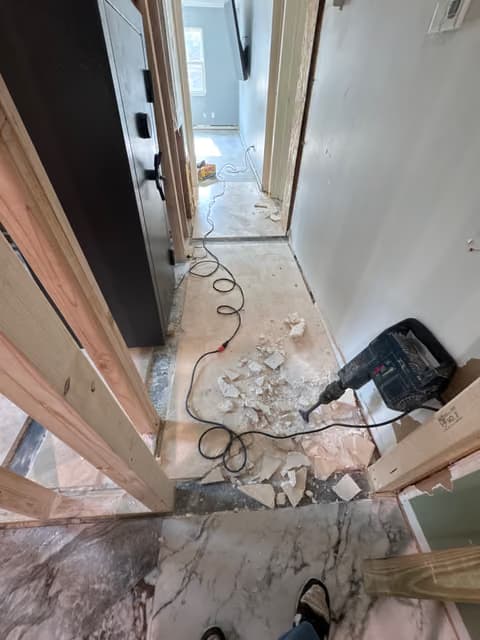 Hallway under renovation with drywall debris and exposed subfloor