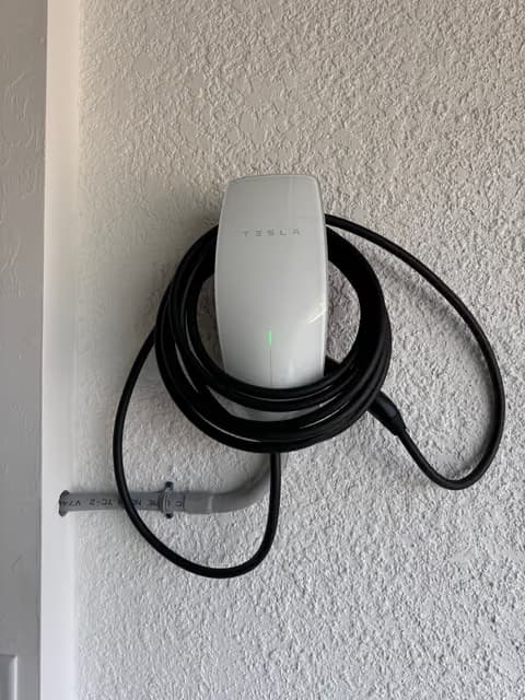 Tesla EV wall charger installed with the cable neatly coiled