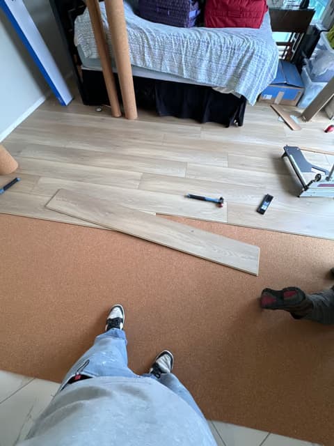 Handyman kneeling while installing a wood flooring plank