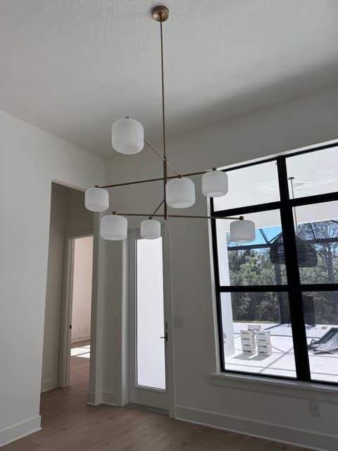 Dining area chandelier with glass globe pendants near tall windows