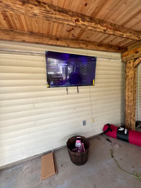 Wall-mounted TV installed on a wood-paneled porch ceiling