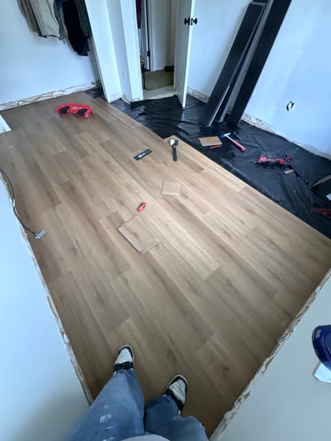 Hardwood flooring installation in progress with tools on the floor