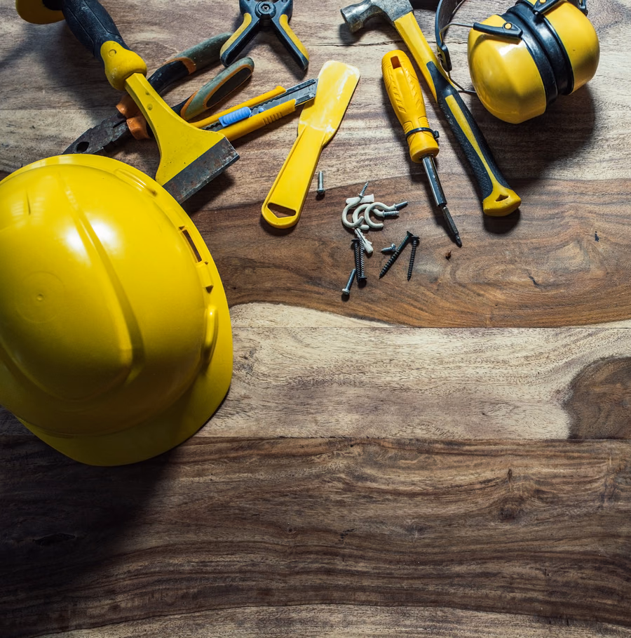Handyman tools and a hard hat laid out on a wood workbench